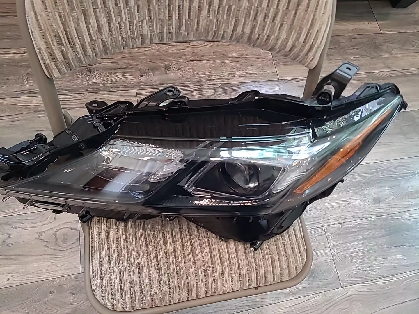 A car headlight sitting on top of a wooden chair.