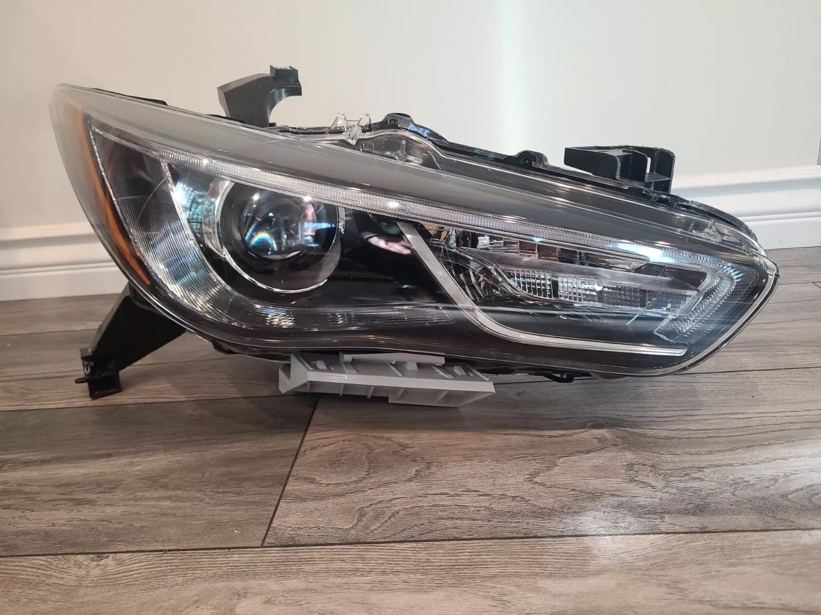 A car headlight that is broken and sitting on the floor.