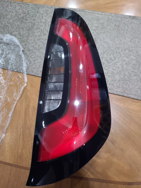 A red and black car tail light on top of a wooden table.