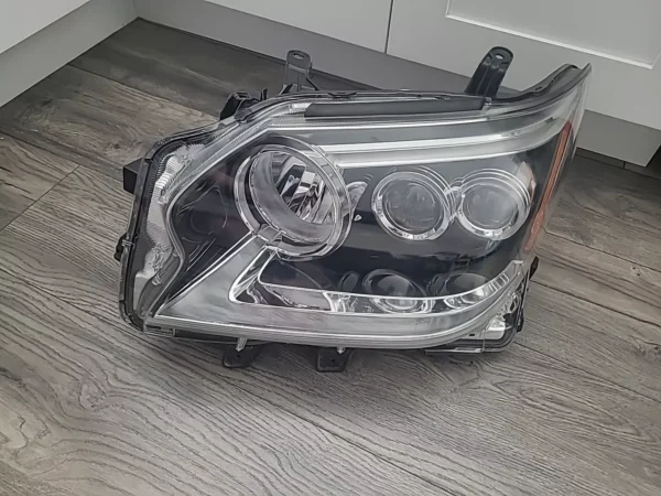 A car headlight that is broken and sitting on the floor.