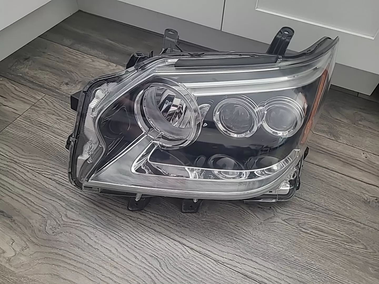 A car headlight that is broken and sitting on the floor.