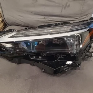 A car headlight that is broken and sitting on the floor.