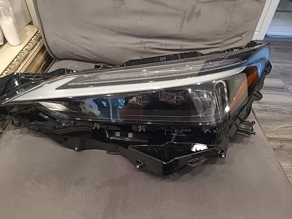 A car headlight that is broken and sitting on the floor.