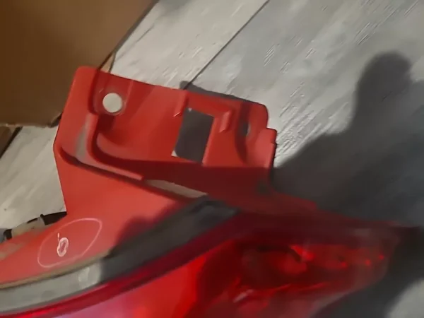 A red piece of plastic sitting on top of a wooden floor.