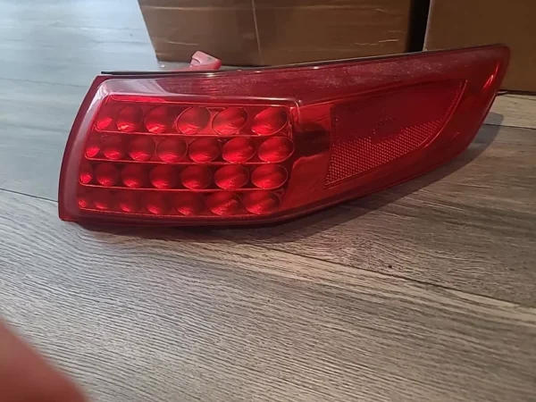 A red tail light sitting on top of a wooden floor.