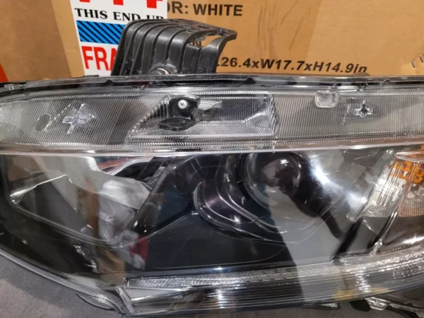 A car headlight with the lights on and some other items in it