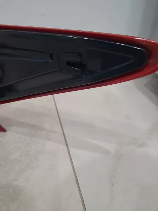 A close up of the side of a red surfboard.