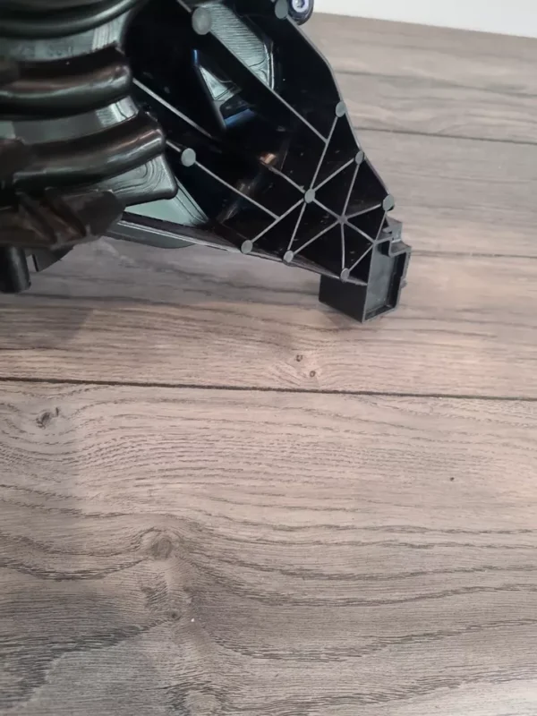 A robot is standing on the floor and looking at it.