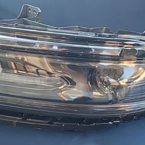 Close-up of a damaged car headlight with visible dents and scratches.