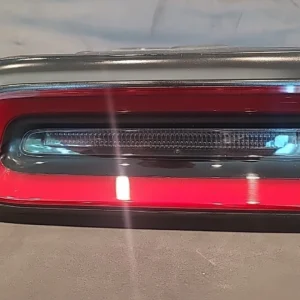 Close-up of a red car's rear tail light with a clear lens and horizontal light strips.