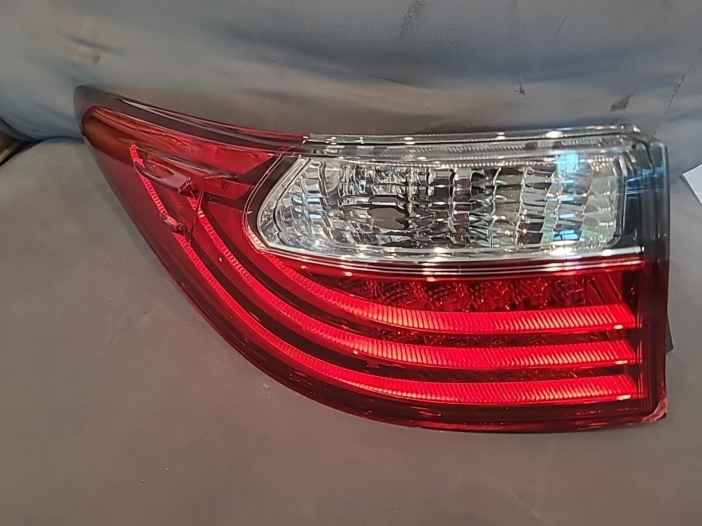 Close-up of a red and clear car tail light on a gray vehicle.