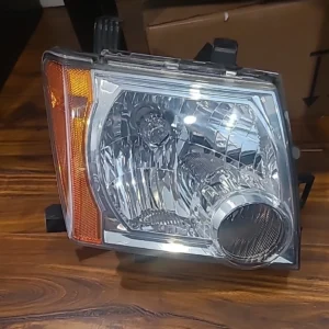 Close-up of a car headlight assembly on a wooden surface.