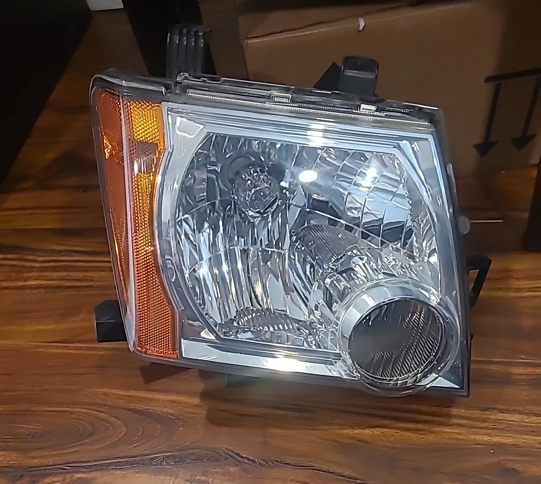 Close-up of a car headlight assembly on a wooden surface.