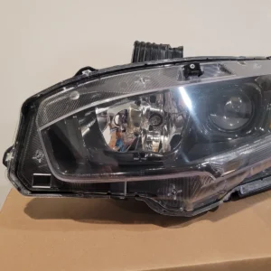 Close-up of a car headlight on a cardboard surface.