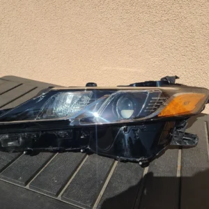 Black car headlight assembly with clear lens and amber reflector.