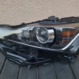 Close-up of a detached car headlight assembly on the ground.