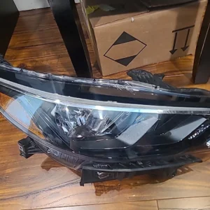 A close-up of a car headlight assembly on a wooden floor.