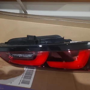 A red and black car tail light assembly on a cardboard surface.