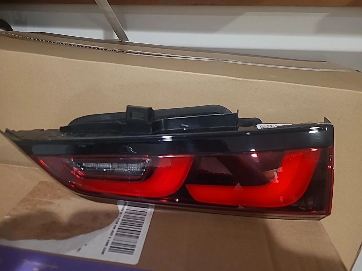 A red and black car tail light assembly on a cardboard surface.