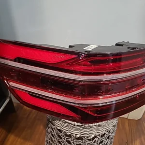 Close-up of a modern car's red taillight with clear sections, placed indoors on a wicker stand.