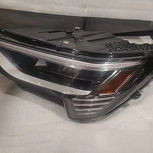 Close-up of a car headlight assembly on a white surface.